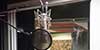 View into the control room from our vocal booth, featuring our Neumann U87 large-diaphragm condenser microphone.